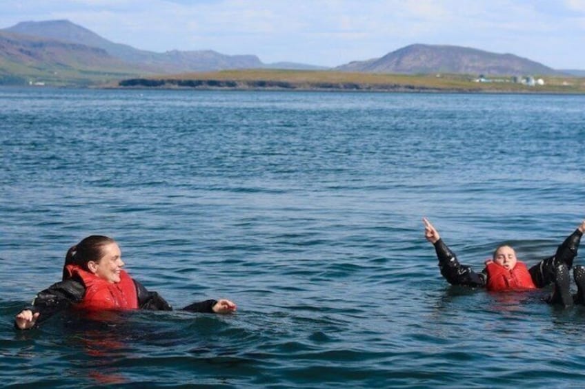 Two people floating on water with mountains in the background. 4