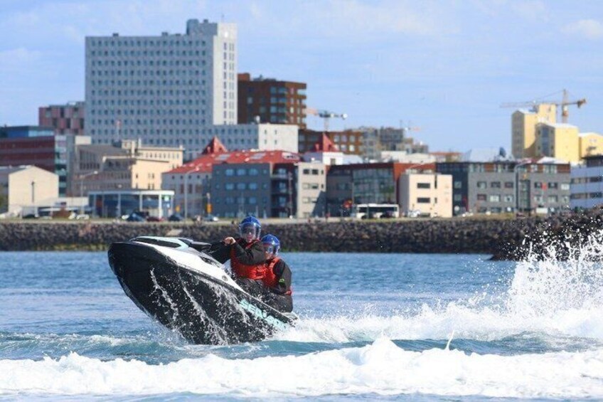 A person jet-skiing on water with buildings in the background. 5