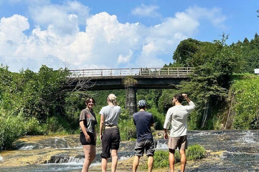 A group of people standing on a rocky outcrop near a bridge over a river. 3