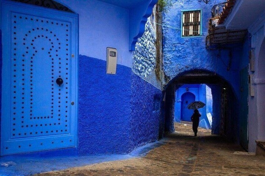 A narrow alleyway with blue-painted walls and a blue door. 1