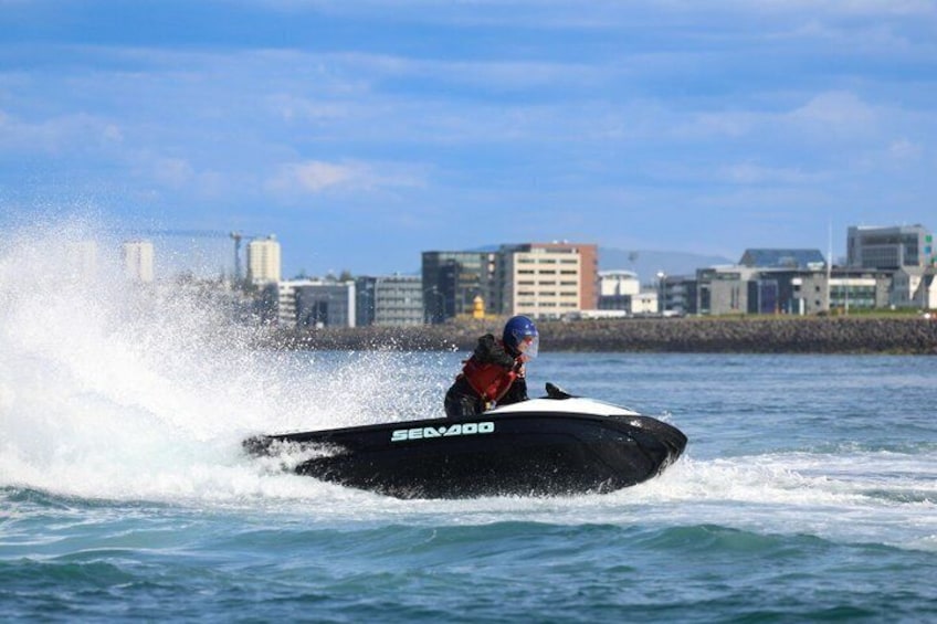 A person jet-skiing on a body of water with a cityscape in the background. 4