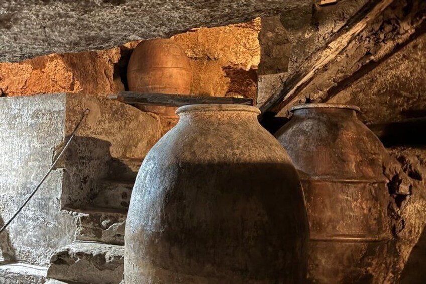 A stone wall with large, weathered pottery vessels. 3