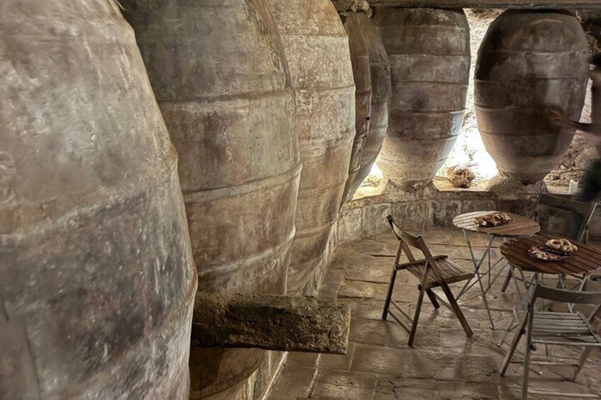 An ancient stone structure with large stone walls and a wooden table with chairs. 5