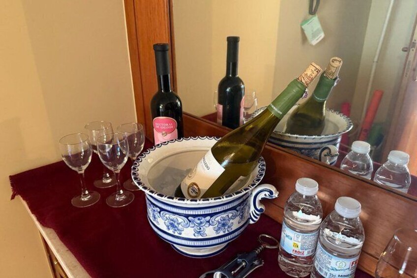 A blue and white bowl with two champagne bottles, empty wine glasses, and water bottles on a table. 2