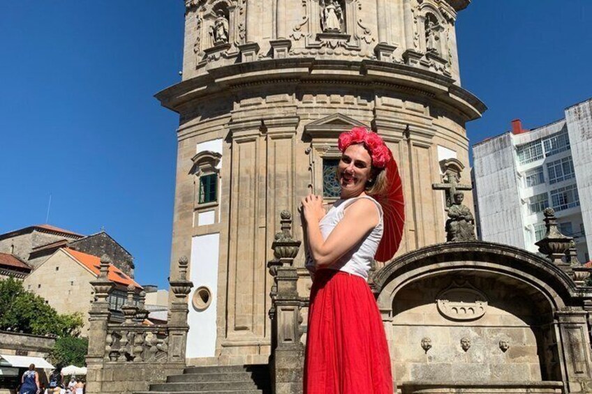 A person in a red dress standing in front of a historical building with intricate carvings and a clock. 1