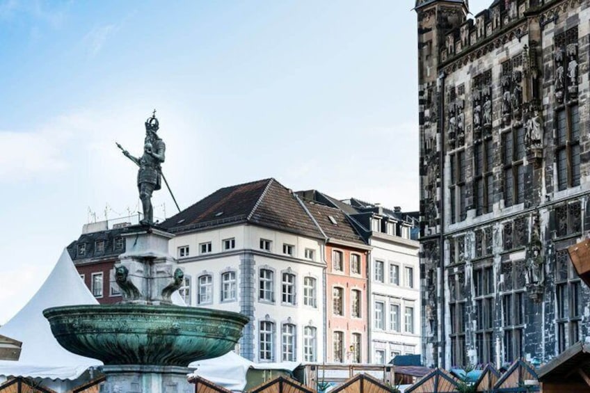 A historic building with a statue on top, a fountain in the foreground, and another building with intricate facade details. 5