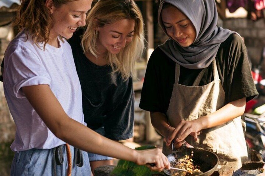 Three people cooking outdoors, with one person stirring a pot. 2