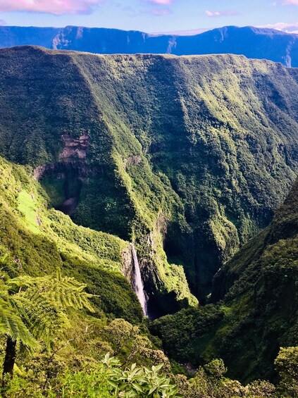 A lush green valley with a waterfall cascading down a steep cliff. 5
