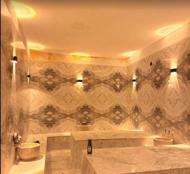 A bathroom with marble walls, a bathtub, and a sink. 5