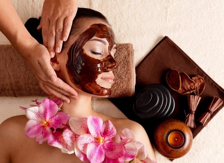A person receiving a facial treatment with a mask, surrounded by spa items like a candle, flowers, and a tray. 3