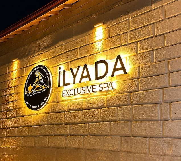 A brick wall with illuminated signage for 'Ilyada Exclusive Spa' and a logo featuring a mermaid. 2