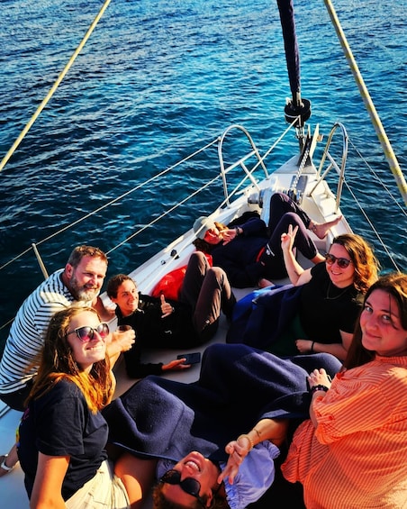 A group of people on a sailboat with the ocean in the background. 2