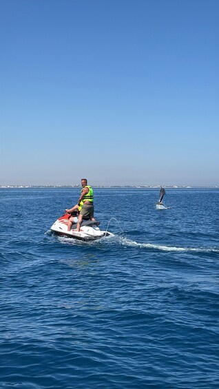 A person jet-skiing on a body of water with a distant shoreline in the background. 1