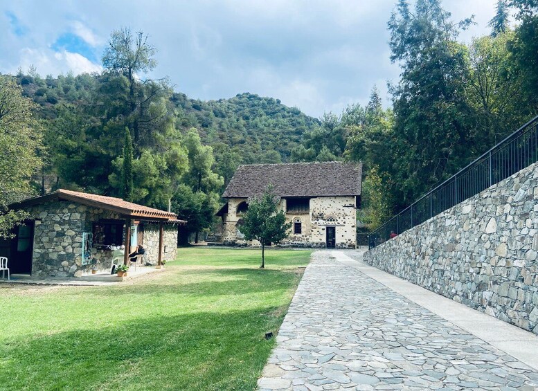 A stone building with a tiled roof, surrounded by a stone wall and a paved pathway. 2