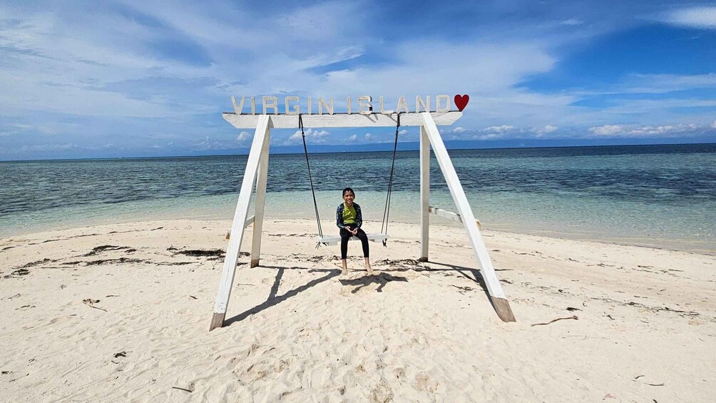 A swing set on a beach with a sign that reads 'VIRGIN ISLAND' and a heart symbol. 3