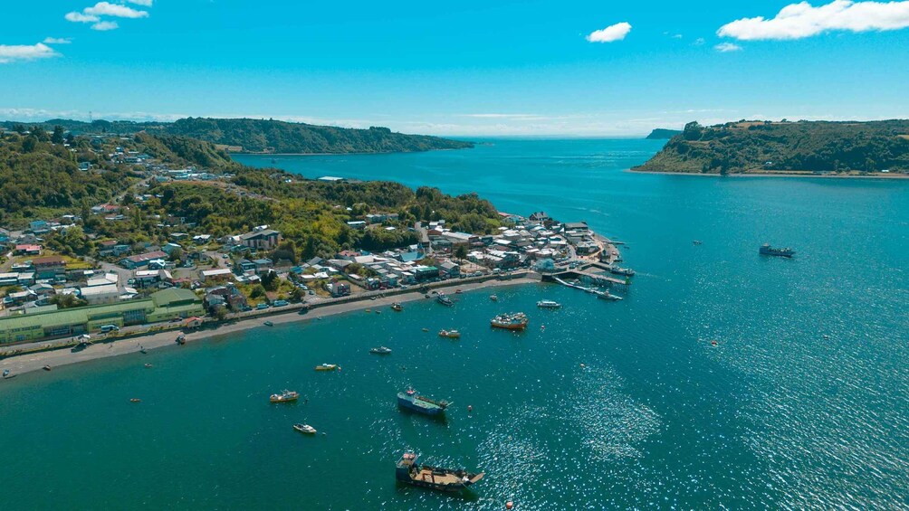 An aerial view of a coastal town with a marina, boats, and surrounding hills. 1