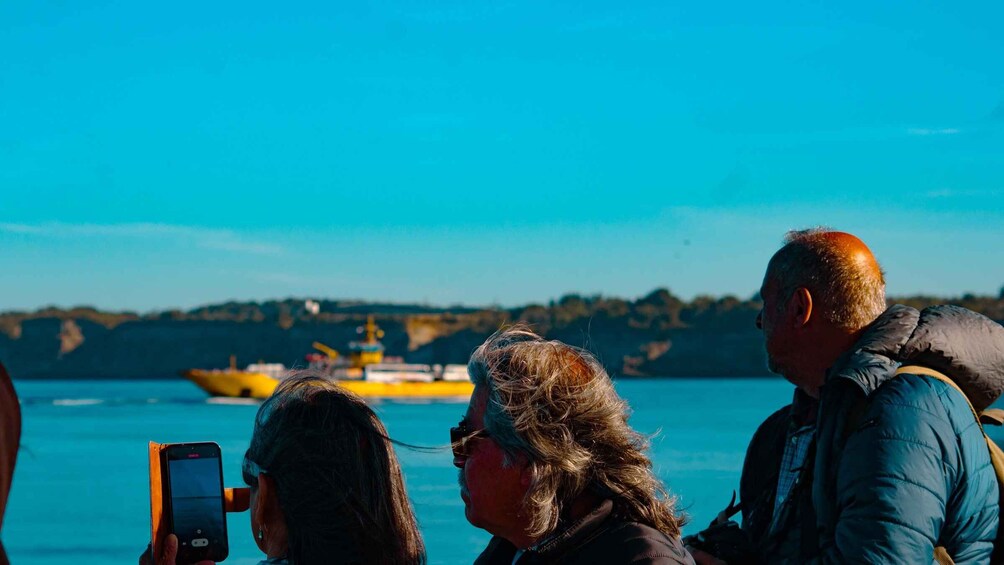 A group of people on a boat, with a yellow ship in the background. 3