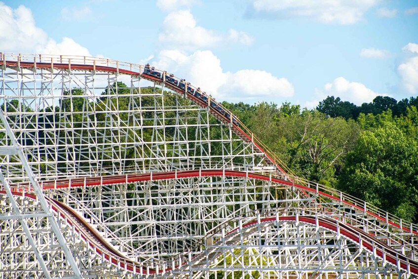 A roller coaster with red tracks winding through a steel framework. 5