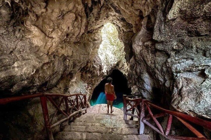 A cave with a person walking down a stone staircase. 1