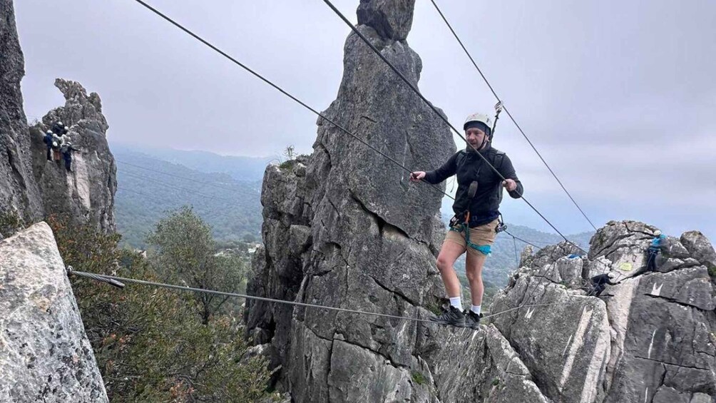 A person rappelling down a rocky cliff with a harness and ropes. 3