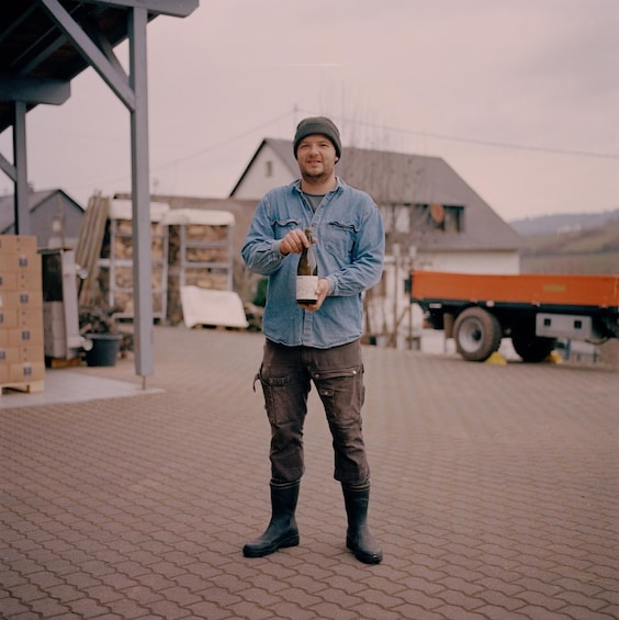 A person standing on a paved surface holding a bottle. 3