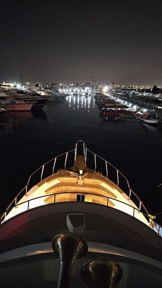 A nighttime marina with boats docked and lights reflecting on the water. 5