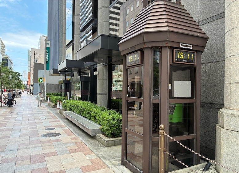 A pedestrian walkway with a bus stop, a green bicycle, and a building with a digital clock. 4