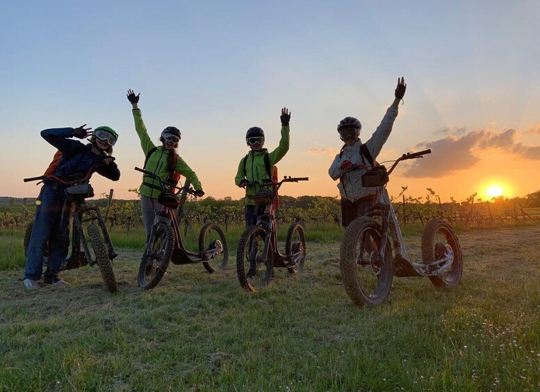 Four people on mountain bikes in a grassy field with a sunset in the background. 4