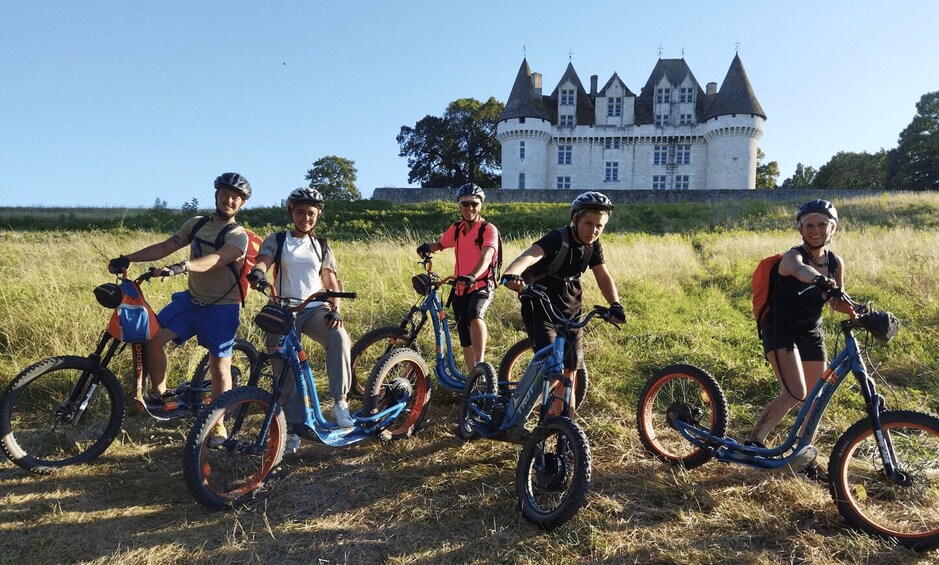 A group of cyclists on a trail with a castle in the background. 2