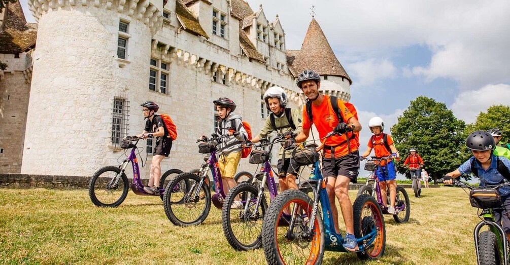 A group of people on bicycles in front of a historic castle. 1