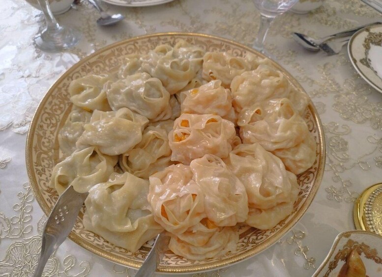 A plate of dumplings with a fork and spoon on a table with a floral tablecloth. 4