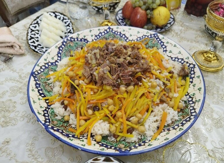 A large plate of food with shredded carrots, chickpeas, and shredded meat on top of rice. 2