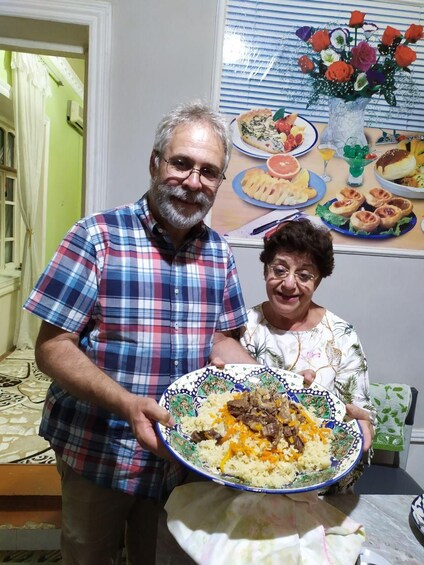 A man and a woman holding a large plate of food. 5
