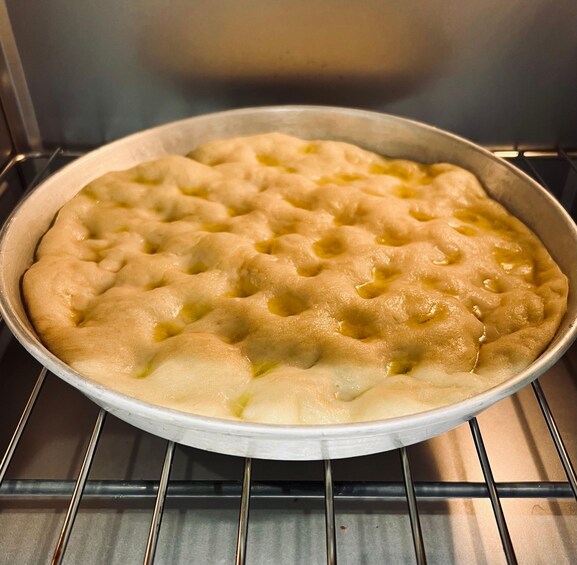 A round baking dish with a golden-brown crust, placed inside an oven. 3