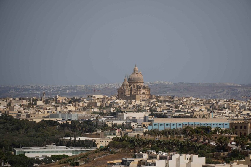 A cityscape with a prominent domed building in the center, surrounded by densely packed residential buildings. 2