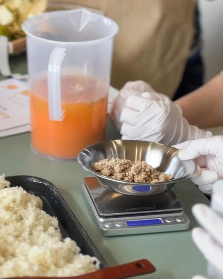 A person weighing food items on a digital scale, with a measuring cup and a bowl of rice nearby. 4