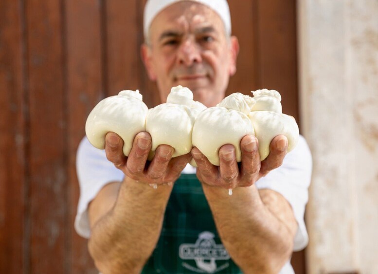 A person holding several white dough balls. 1