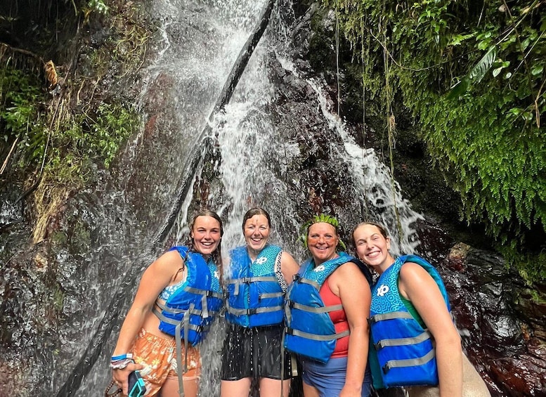 A group of people standing in front of a waterfall surrounded by greenery. 2