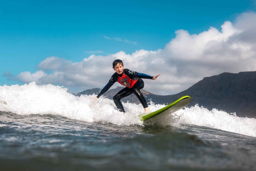 A person surfing on a wave with mountains in the background. 5