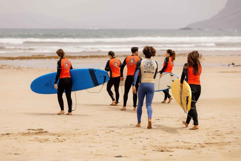 A group of people walking on a beach with surfboards. 4