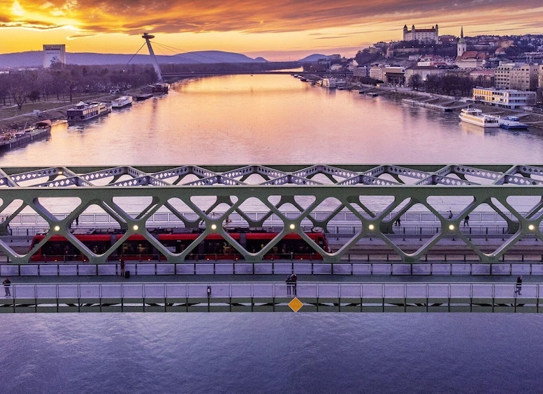 A river with boats, a bridge, and a cityscape during sunset. 5