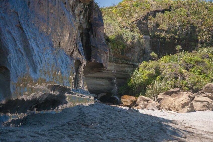 A coastal rock formation with a narrow passage leading into a cave. 1
