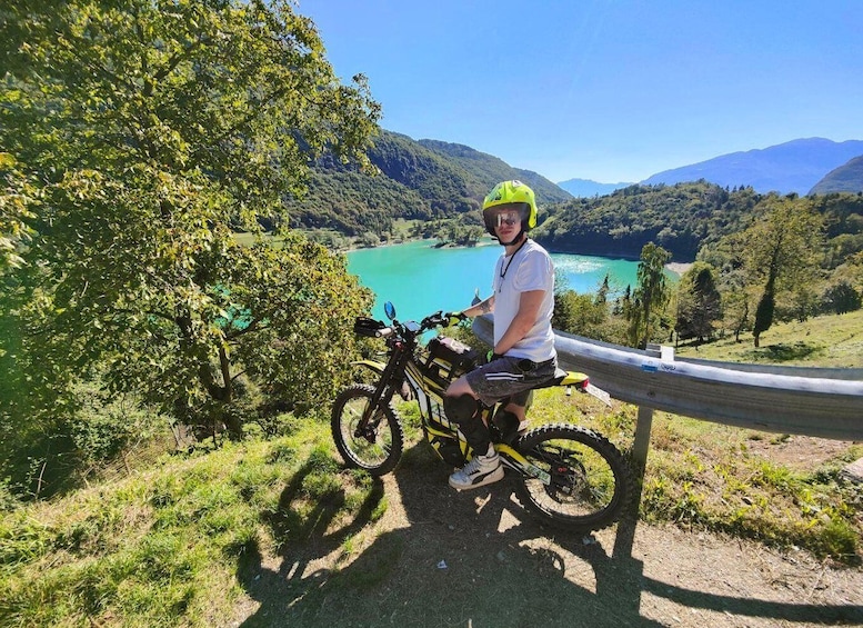 A person on a mountain bike with a scenic view of a lake and mountains in the background. 2