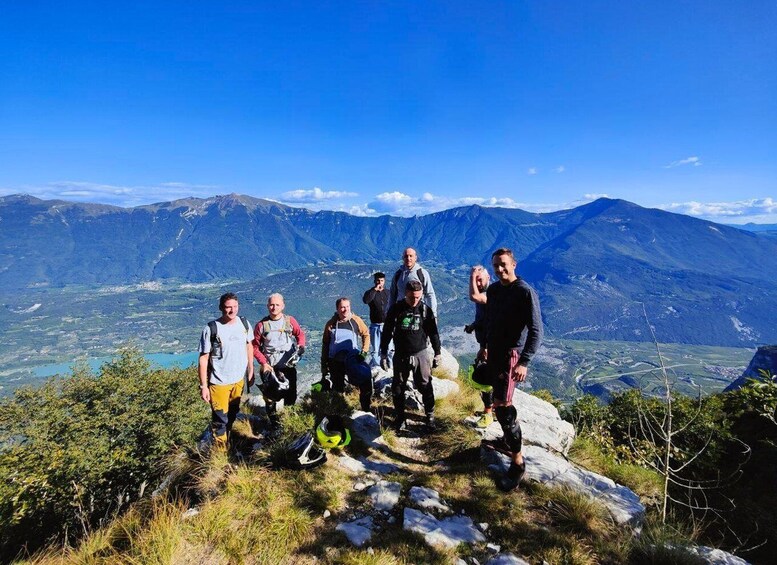 A group of hikers on a mountain peak with a scenic view of a valley and mountains in the background. 4
