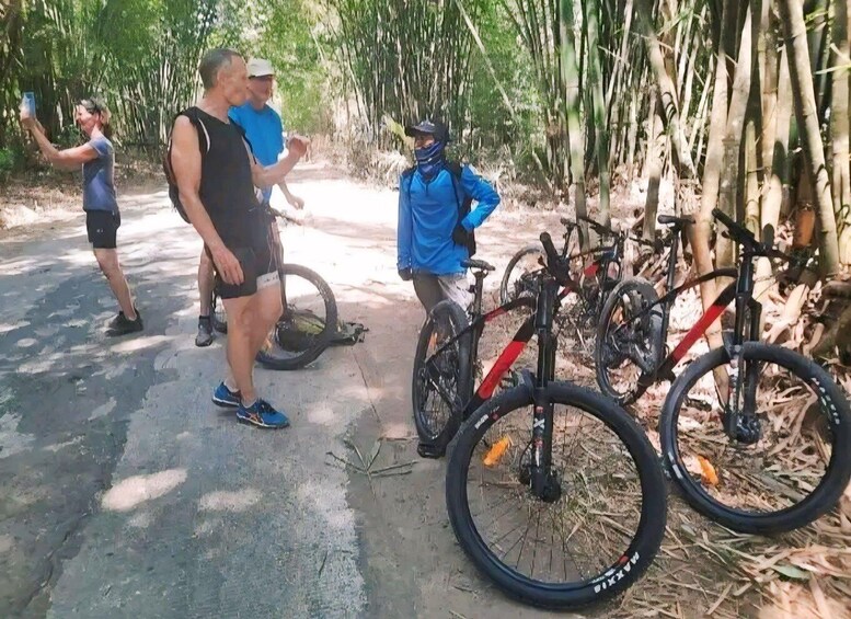 A group of people near bicycles in a forested area with bamboo trees. 5