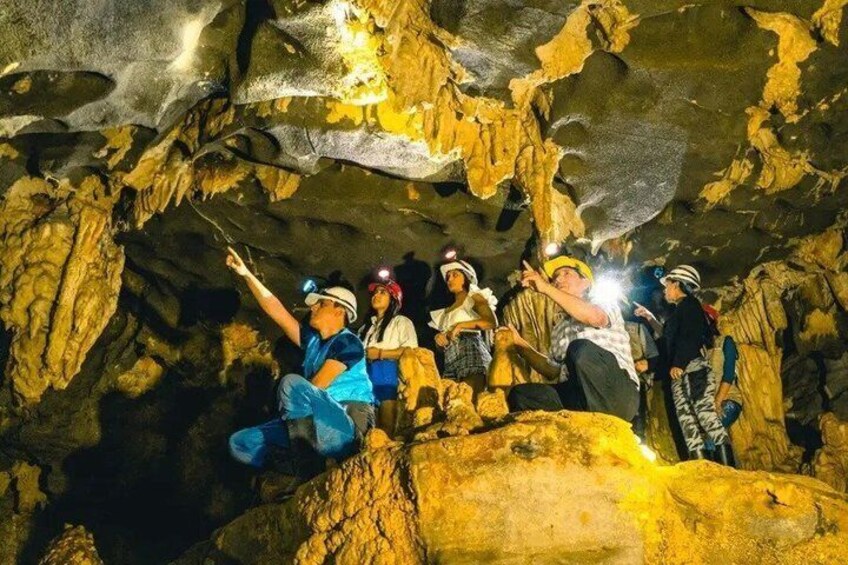 A group of people inside a cave with rocky formations and a large boulder. 4