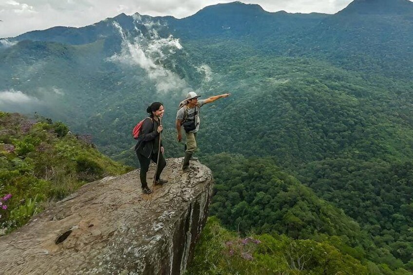 Two hikers on a mountain ridge with a forested valley below. 4