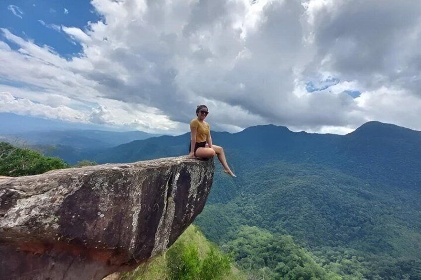 A person sitting on a rock with a mountainous landscape in the background. 2