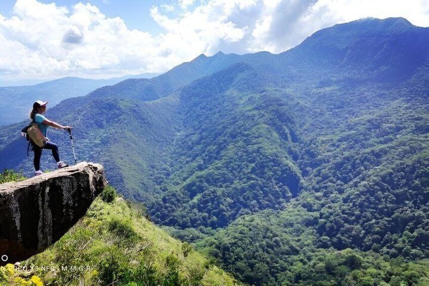 A person hiking on a cliff overlooking a lush valley. 3
