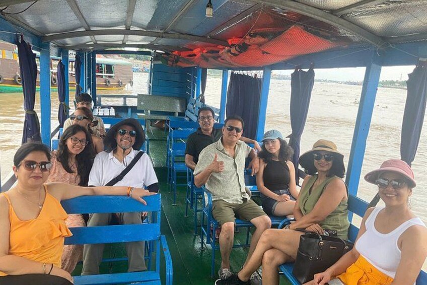 A group of people on a boat with blue railings and a covered upper deck. 3
